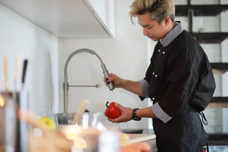 Asian cook in the kitchen prepares food in a cook suitの写真素材