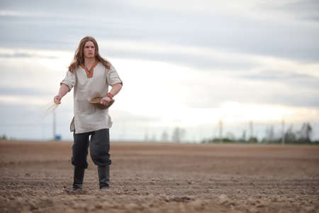 A young peasant sows the field with grainの写真素材