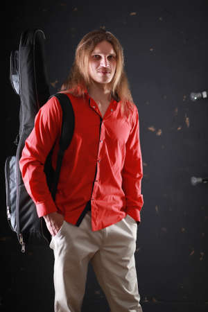 Young man with long hair with a guitarの写真素材