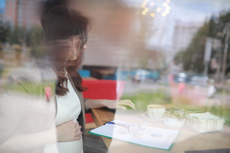 Pregnant woman working on computer in cafeの写真素材