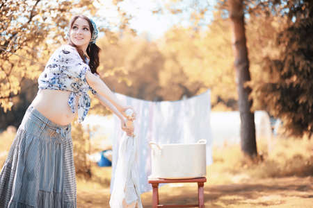 Pregnant woman hanging sheets on the rope for dryingの写真素材