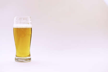 A stack of vintage books and a mug of light beerの写真素材