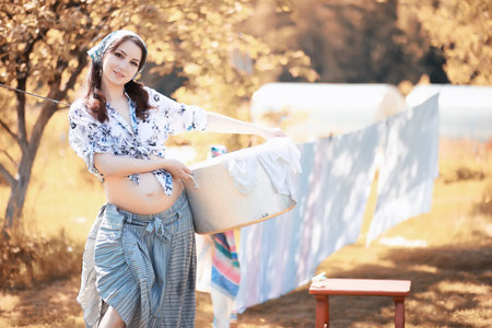 Pregnant woman hanging sheets on the rope for drying