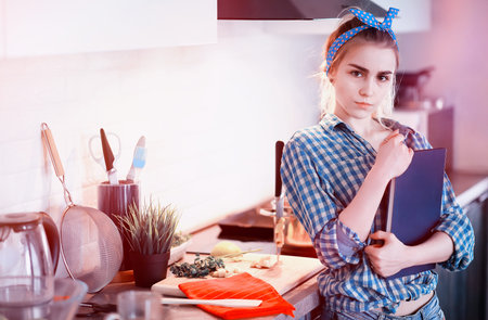 A cute young girl in the kitchen prepares foodの写真素材