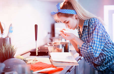 A cute young girl in the kitchen prepares foodの写真素材