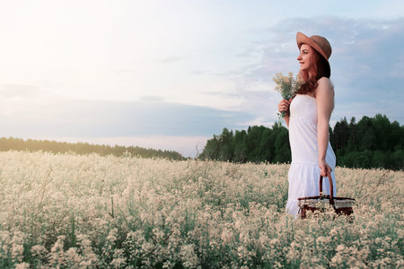 Girl in white dress in a field of yellow flowers blossomingの写真素材