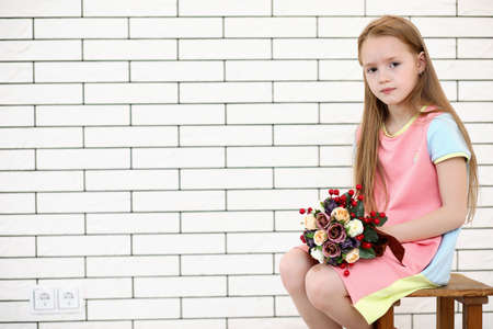 little girl is sitting on a chairの写真素材