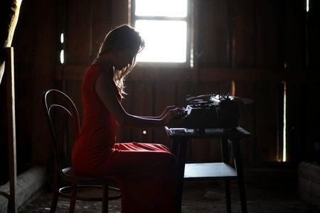 A girl in retro style prints on an old typewriter