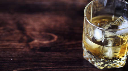 Whiskey with ice with a glass. Cubes of ice on a wooden table anの写真素材