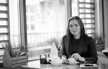 Girl in a cafe sitting and drinking teaの写真素材