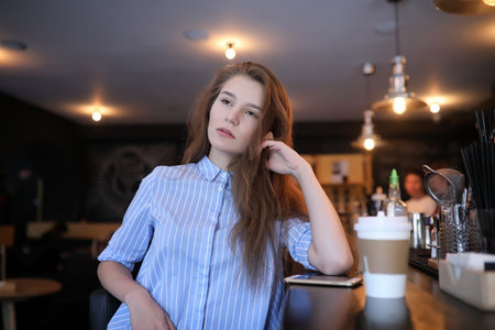 Girl with coffee. Young beautiful girl is sitting in a cafe