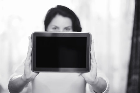 The girl is holding a tablet. The girl has a computer with a scr