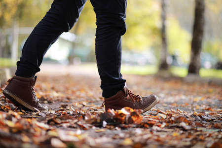 Autumn Park man walking along a path in foliageの写真素材