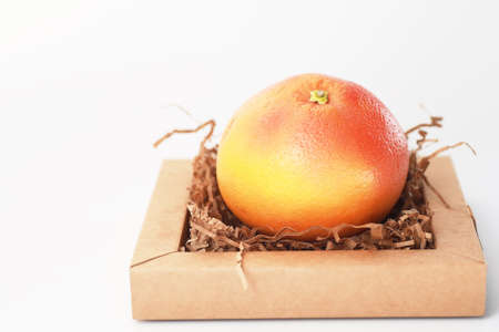 Fresh juicy grapefruits on a white table in a small basketの写真素材