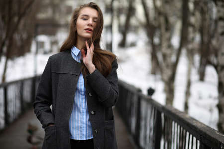 Young adult girl in coat on the streetの写真素材