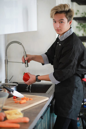 Asian cook in the kitchen prepares food in a cook suit