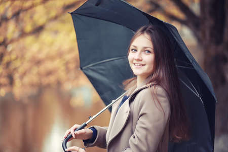 Young girl in a coat in autumn  parkの写真素材