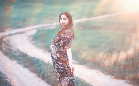 Pregnant girl in a dress in natureの写真素材