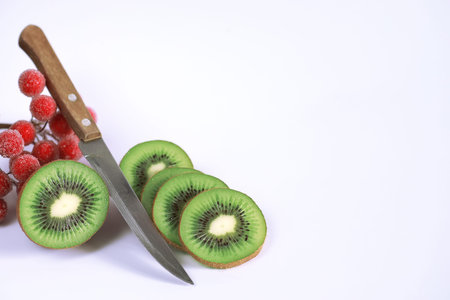 A kiwi fruit is sliced into pieces on a white background.