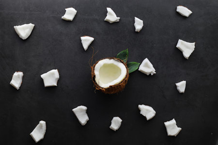 Coconut on a dark stone table. Coconut oil and chips.