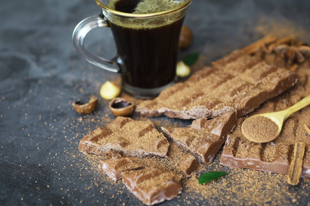 A bar of milk chocolate on the table. Chocolate with nuts and cinnamon flavor.