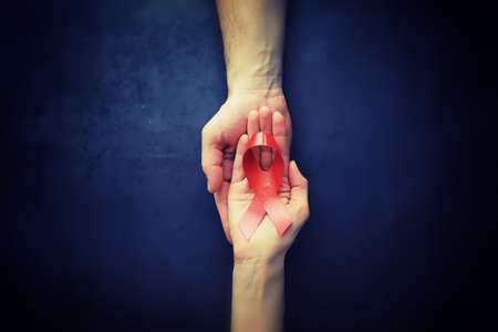 Symbol of human immunodeficiency virus disease. Red ribbon. A helping hand and support. Background.の写真素材