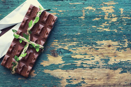 A bar of milk chocolate on the table. Chocolate with nuts and cinnamon flavor.の写真素材