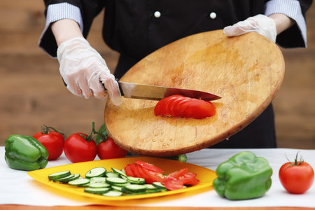 The cook cuts fresh farm vegetables for dinner on the tableの写真素材