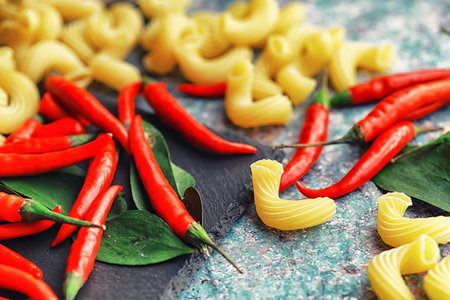 Uncooked pasta on a stone background. With seasonings and spices, spicy chili peppers and spices.の写真素材