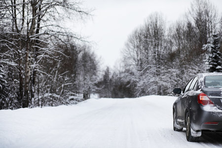 the car stands on a snow-covered road in a wintertime cloudy dayの写真素材