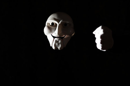White scary mask on a black background with whites hands.