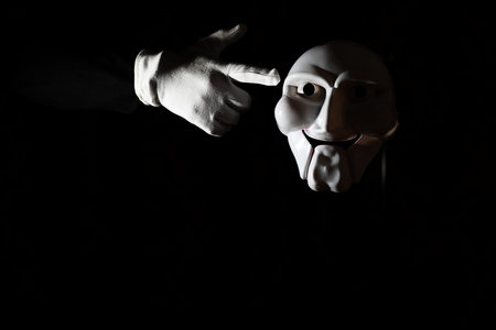 White scary mask on a black background with whites hands.