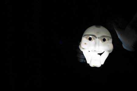White scary mask on a black background with whites hands.の写真素材