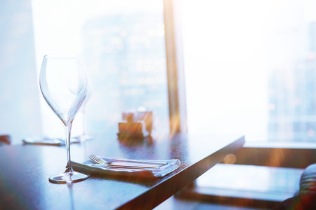 Cocktail glasses on the windowsill by the glass of a tall buildingの写真素材
