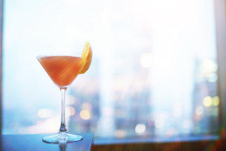 Cocktail glasses on the windowsill by the glass of a tall buildingの写真素材