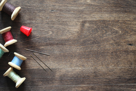 Sewing thread on a wooden background. Set of threads on bobbins retro style. Vintage accessories for sewing on the tableの写真素材
