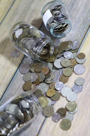Accumulated coins stacked in glass jars on the floorの写真素材