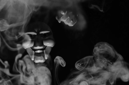 White scary mask on a black background with whites hands.