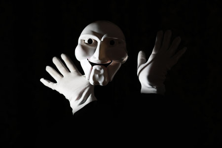 White scary mask on a black background with whites hands.の写真素材