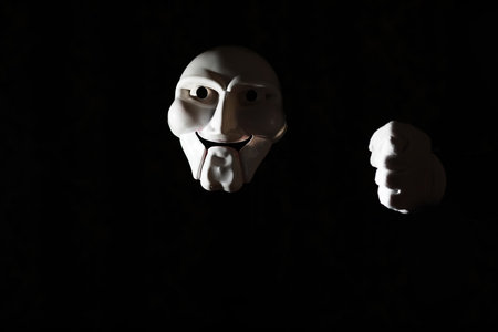 White scary mask on a black background with whites hands.の写真素材