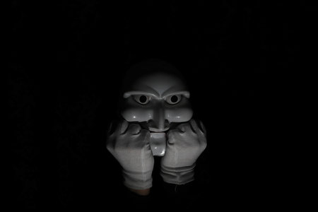 White scary mask on a black background with whites hands.の写真素材