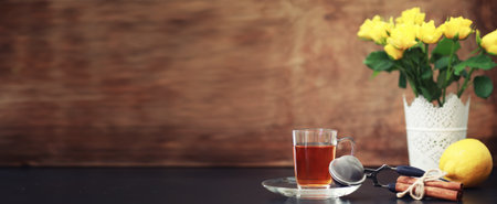A cup with tea on the table and flowers in a vaseの写真素材