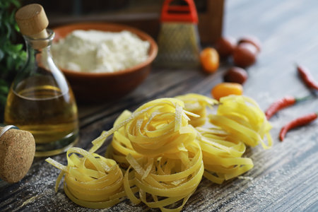 Pasta uncooked on the table. Noodles in the form of nests. Flour and seasonings.の写真素材