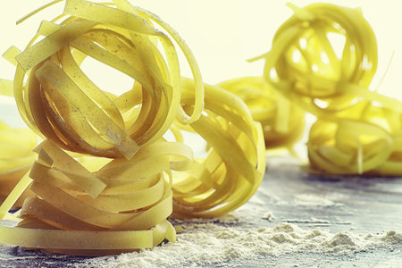 Pasta uncooked on the table. Noodles in the form of nests. Flour and seasonings.の写真素材