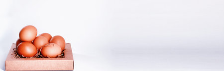 Chicken brown eggs on a white table in a small basketの写真素材