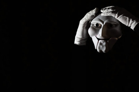 White scary mask on a black background with whites hands.