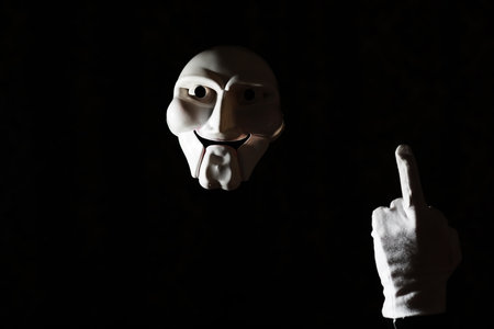 White scary mask on a black background with whites hands.の写真素材