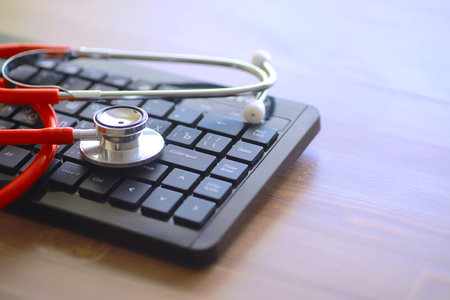 Doctor at his desk in the clinic's office. Stethoscope, test tubes, laptop, prescriptions, glasses on table.の写真素材