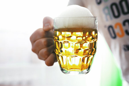 Saint Patrick's Day holiday. National Irish holiday. Green beer Hand with a mug emerald beer in a bar.の写真素材