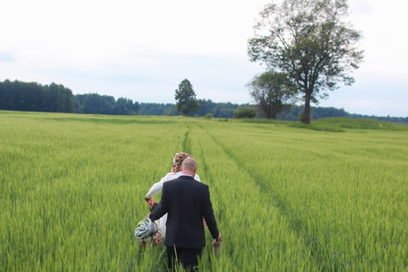Couple lovers walking in a green field in summer dayの写真素材